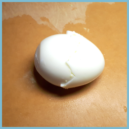 Photo d’un œuf dur avec une forme zigzag découpé à sa ceinture. 