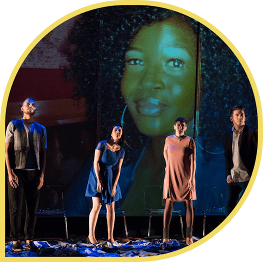 Photo de 4 artistes debout sur une scène avec le visage d’une femme, sur un écran, en arrière-plan.   