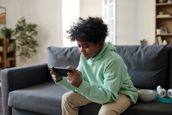 Photo d’un jeune homme assis sur un canapé qui regarde un téléphone intelligent. 