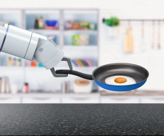 Photographie d’un bras robotisé qui tient une poêle dans laquelle cuit un œuf tourné.