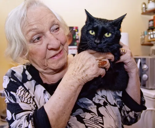 Photographie d’une vielle dame tenant un chat. 