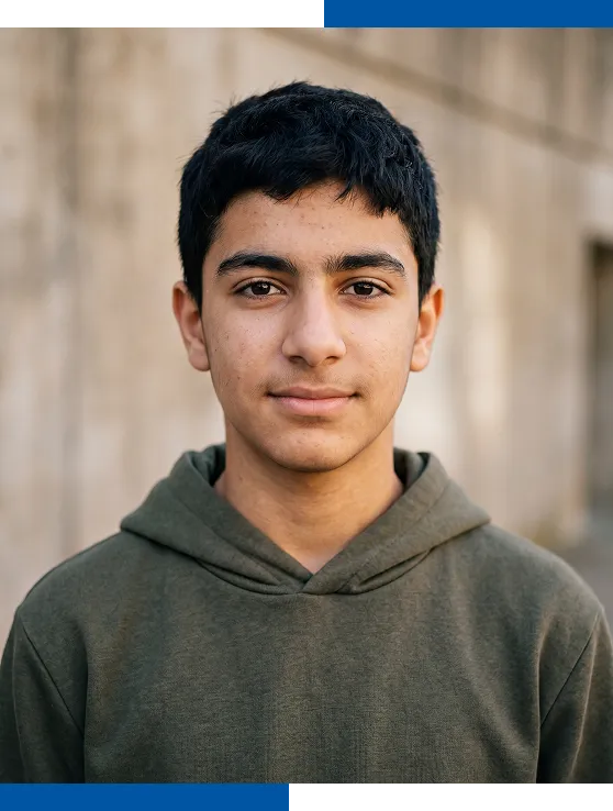 Un adolescent au regard calme esquisse un léger sourire devant un mur de ciment.