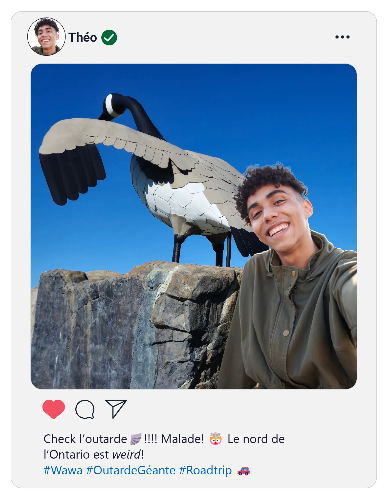 Egoportrait de Théo, souriant, devant la sculpture de l’oie géante sous le ciel bleu vif de Wawa.