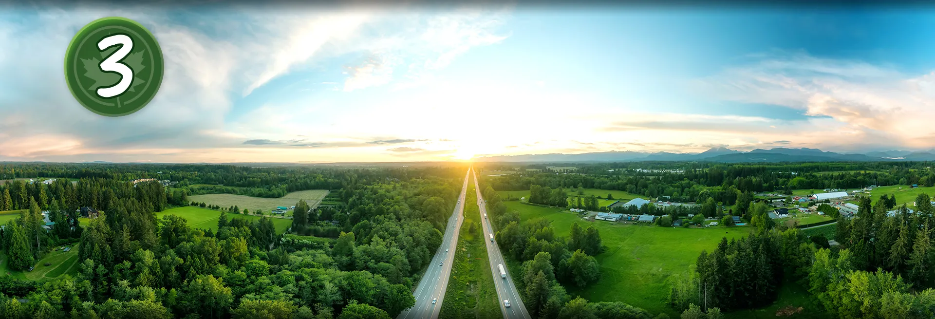 Photo d’une route entourée d’un paysage verdoyant au lever du soleil. Cercle contenant le chiffre 3 et une feuille d’érable.