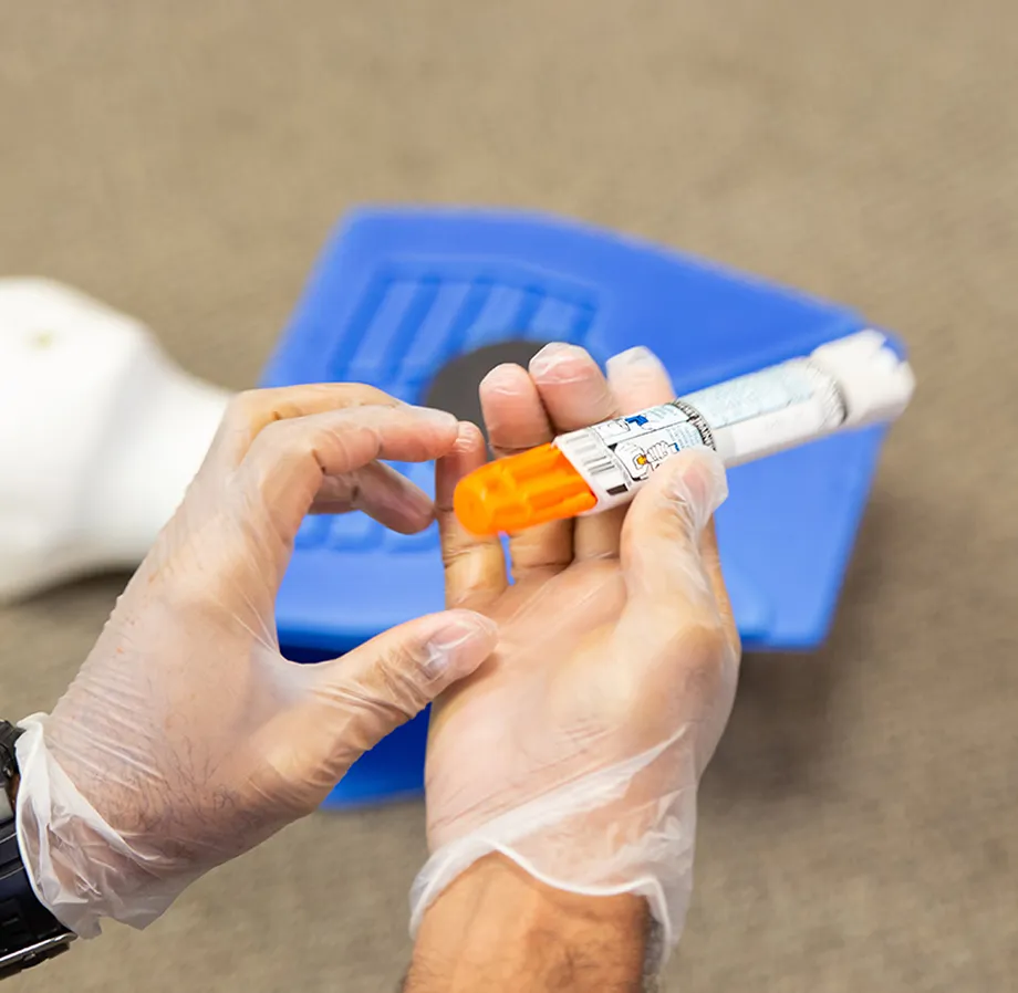 Une personne portant des gants tient un auto-injecteur d’adrénaline ou d’épinéphrine, connu sous la marque de commerce EpiPen.