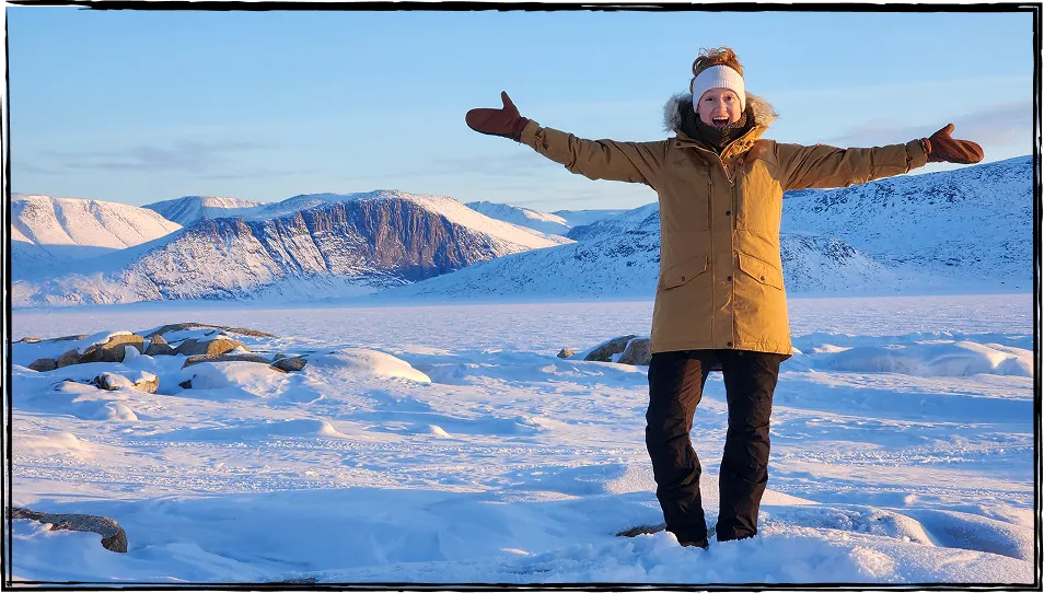 Photo de Nadia Campbell souriante, les bras levés, debout au milieu d’un paysage hivernal.