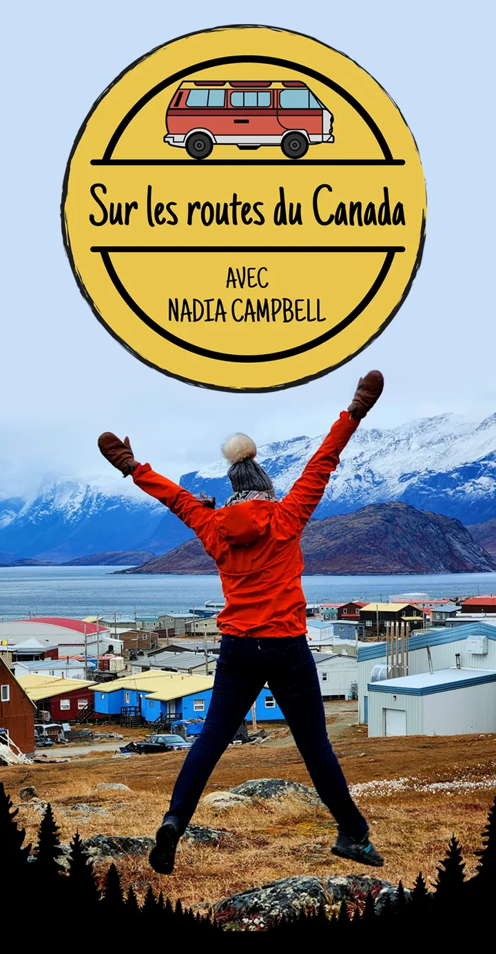 Photo de Nadia Campbell se tenant, les bras levés, devant un paysage de montagnes enneigé et d’un petit village près de l’eau.
