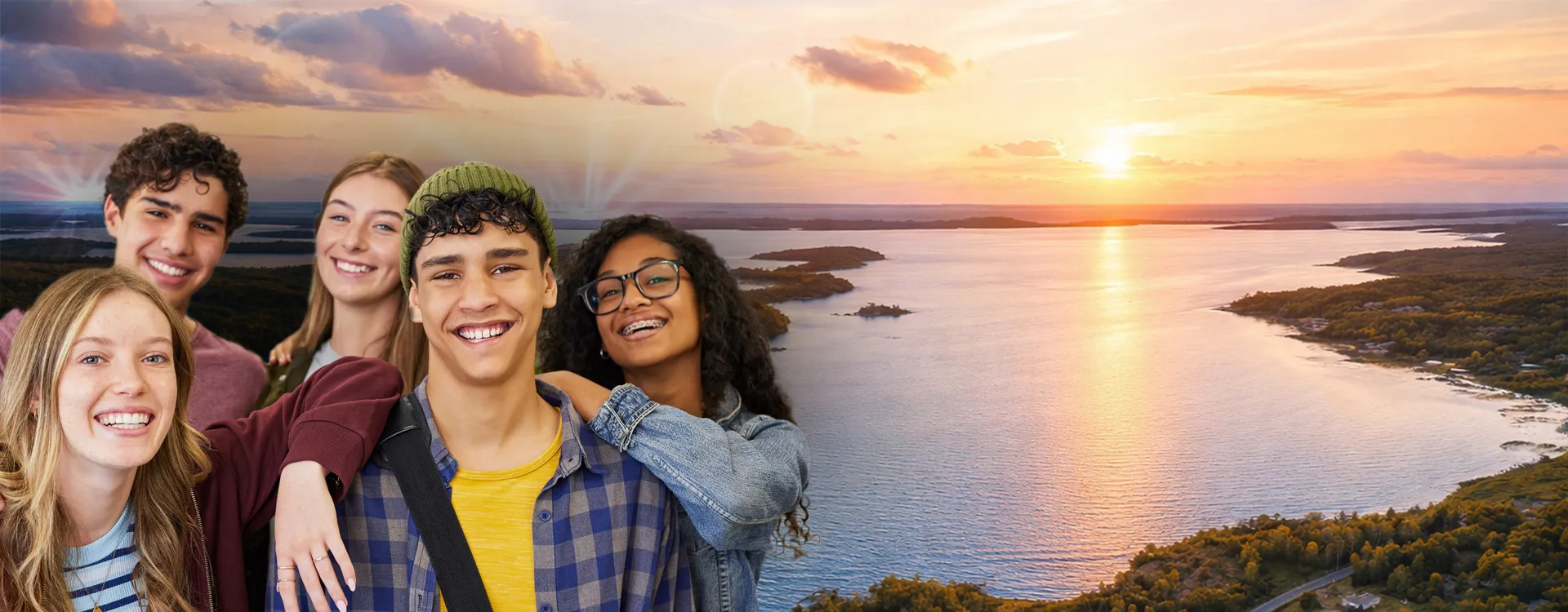 Un groupe d’adolescents souriants se tiennent côte à côte devant un lac sous un soleil couchant.