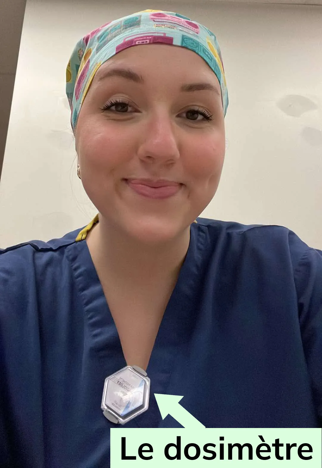 Emma Bissonnette portant un petit chapeau couvrant ses cheveux. Un dosimètre est accroché à son vêtement.