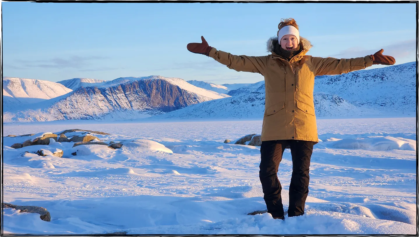 Photo de Nadia Campbell souriante, les bras levés, debout au milieu d’un paysage hivernal.
