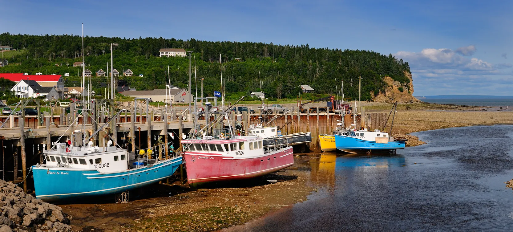Photo d’un quai de pêche où plusieurs bateaux sont amarrés à marée basse. Ici, l’énergie marémotrice permet de produire de l’électricité.