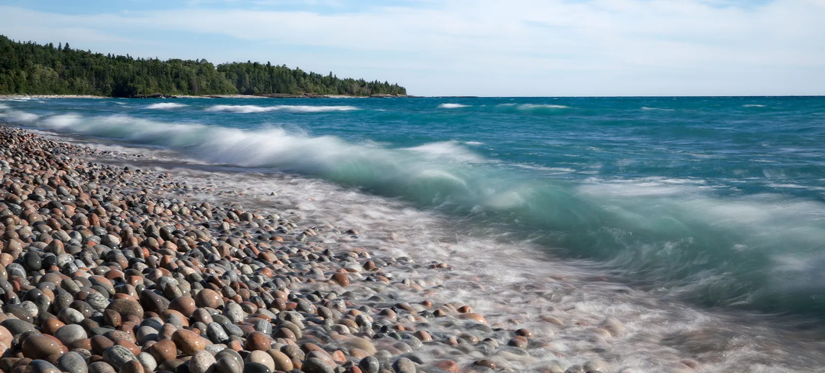 Photo d’une plage couverte de galets frappée par les vagues.