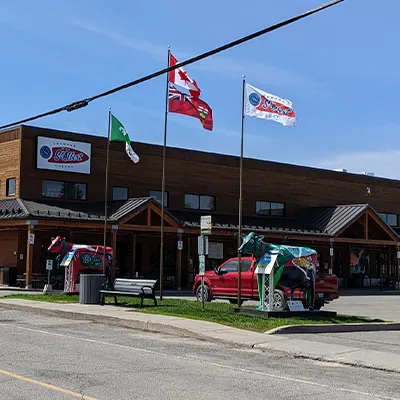 La Fromagerie St‑Albert se dresse sous un ciel clair, avec ses drapeaux flottants et ses sculptures de vaches colorées à l’entrée.