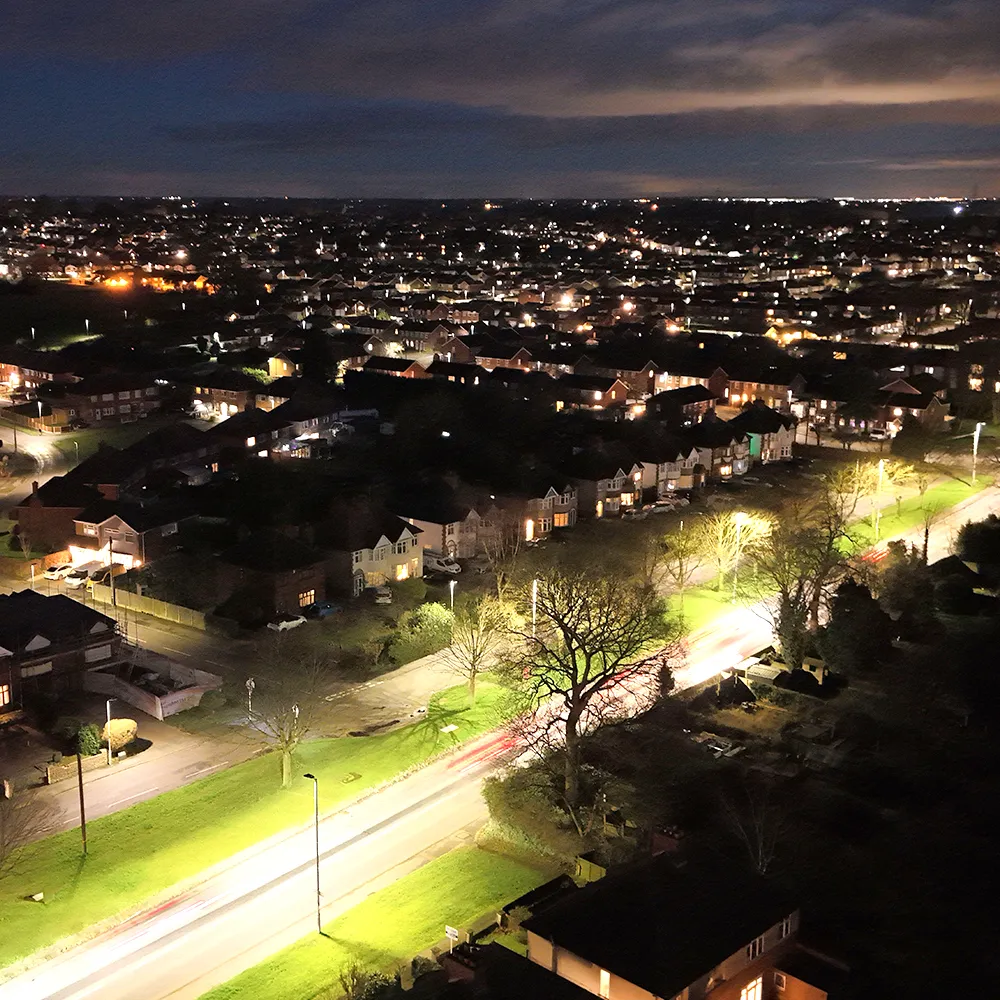Photo d’un quartier de maisons illuminées par hydroélectricité, la nuit.