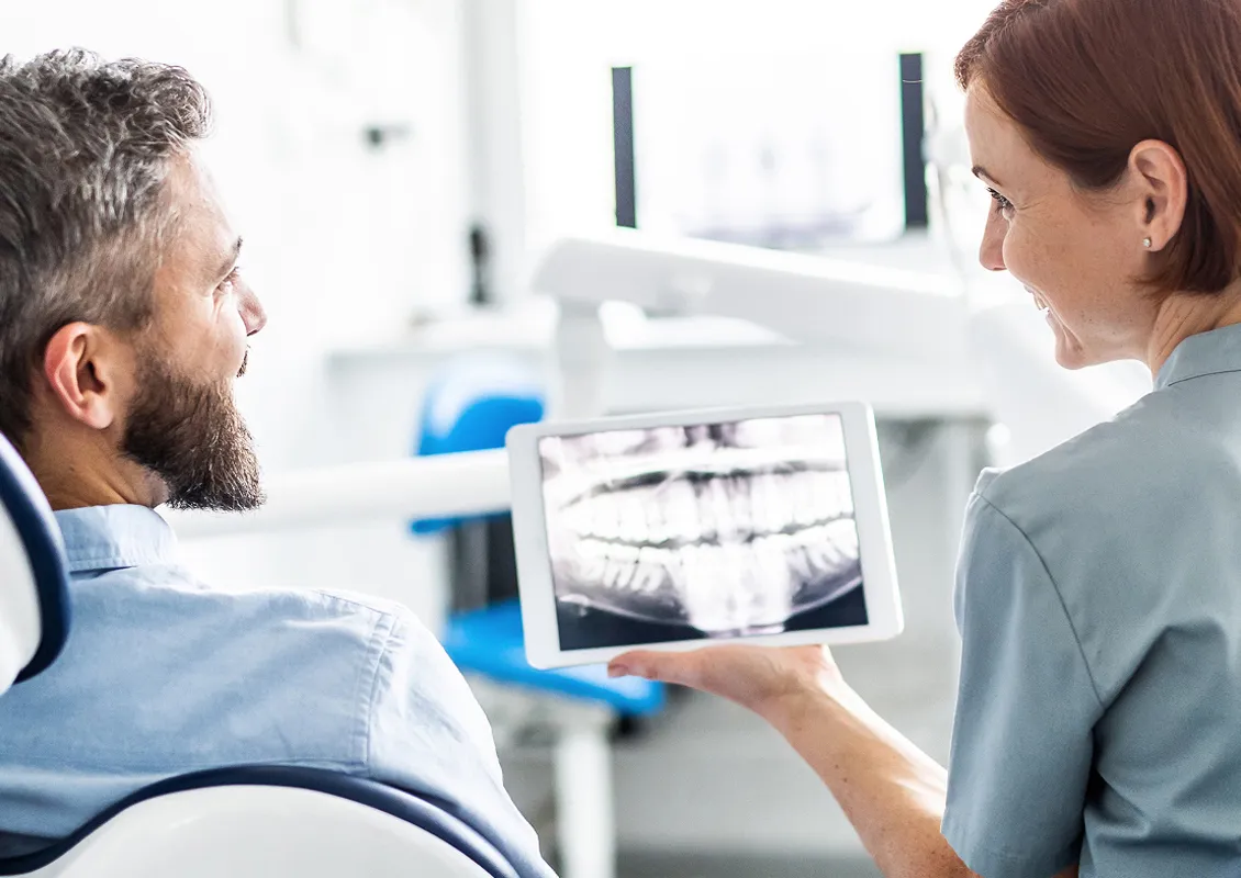 Un patient et une dentiste examinent la radiographie des dents du patient.