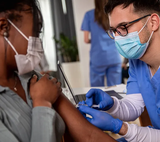 Un infirmier donne un vaccin à une personne à l’aide d’une seringue.