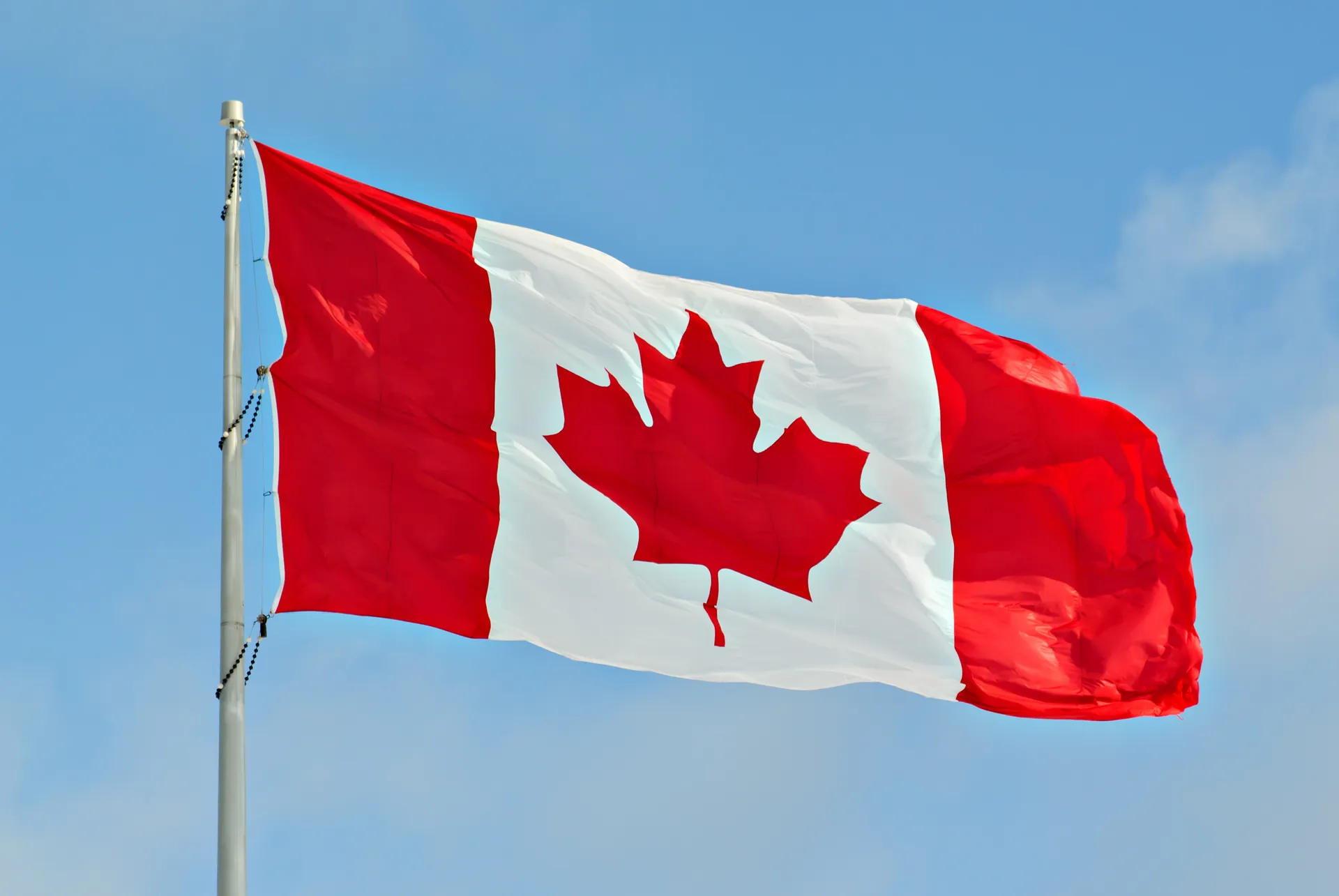 Photo d’un drapeau du Canada flottant dans le ciel bleu.