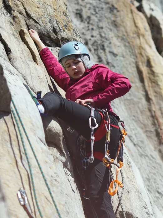 Photo d’une jeune femme qui pratique l’escalade sur une paroi rocheuse.